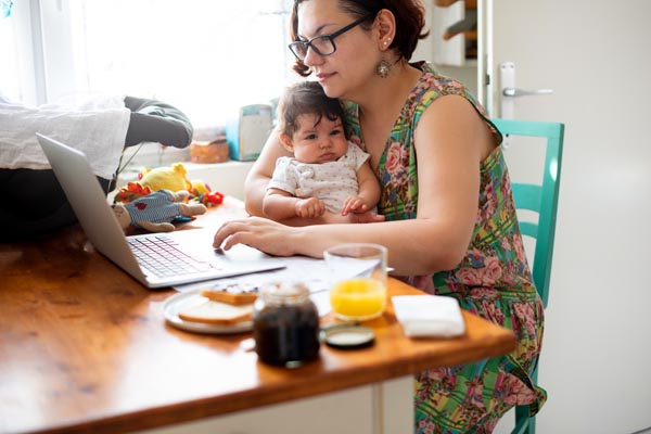 Woman working from home multitasking whilst looking after her child