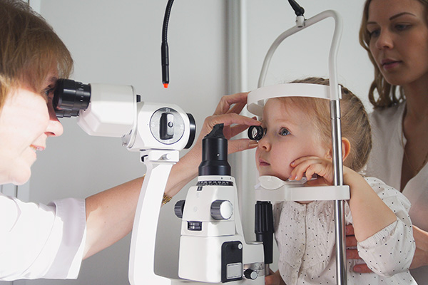 Baby girl during her eye test held by her mother