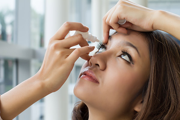 Woman administering eye drops to relief symptoms