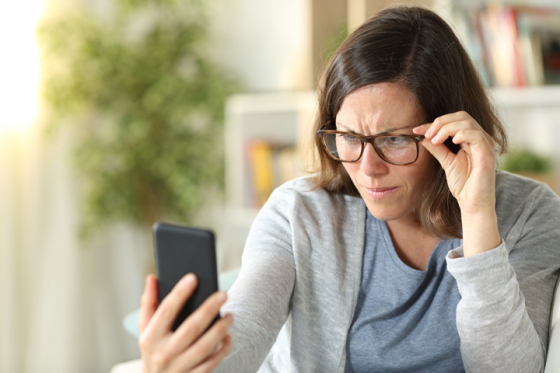 Woman wearing ready readers struggling to see phone screen